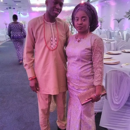 David Olawale Ayinde posing with his wife by wearing clay colored outfit.